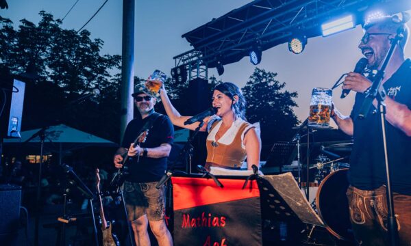 XH2S9813-Enhanced-NR Band mit Bierkrug beim Prosit der Gemütlichkeit im Biergarten vor Sonnenuntergang